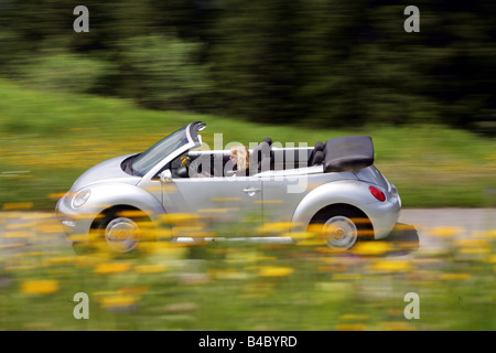 Car, VW Volkswagen New Beetle Convertible, model year 2003-, silver, open top, driving, side view, country road, Summer, landsap Stock Photo