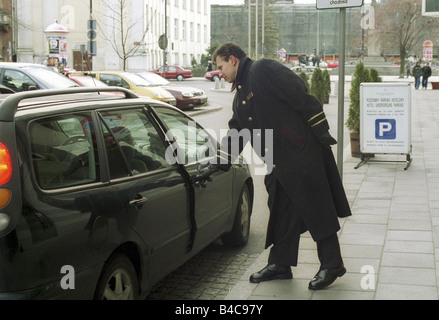 A doorman of the Sheraton Hotel opening the car door for a guest, Warsaw, Poland Stock Photo