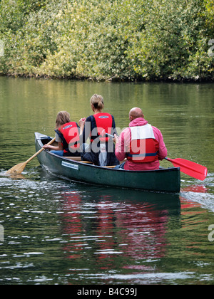 THREE PEOPLE WEARING LIFEJACKETS PADDLING IN CANADIAN CANOE ON RIVER BURE NEAR COLTISHALL NORFOLK ENGLAND UK Stock Photo