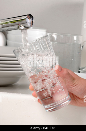 WOMAN FILLING GLASS TUMBLER WITH TAP WATER Stock Photo