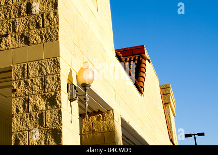Old style lamp mounted on a yellow brick wall on a clear sunny day with blue sky Stock Photo