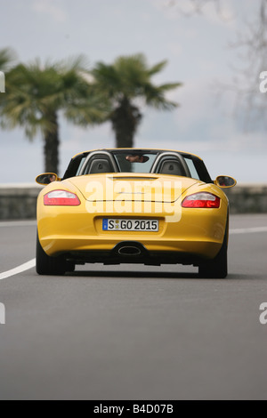 Porsche Boxster Sportpaket, model year 2004-, yellow, driving, diagonal from the back, rear view, country road, open top Stock Photo