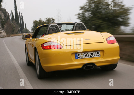 Porsche Boxster Sportpaket, model year 2004-, yellow, driving, diagonal from the back, rear view, country road, landsapprox.e, o Stock Photo