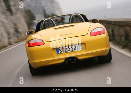 Porsche Boxster Sportpaket, model year 2004-, yellow, driving, diagonal from the back, rear view, country road, open top Stock Photo