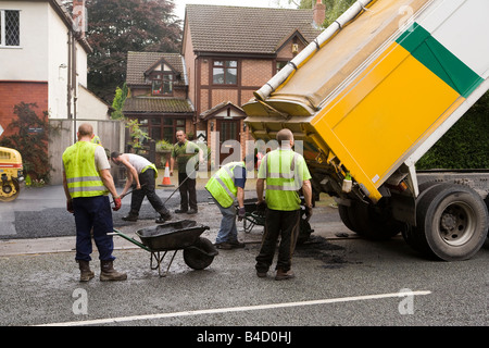 Home improvements gang of workers laying new tarmac domestic drive Stock Photo