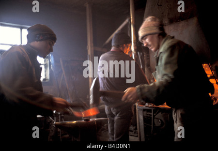 Blacksmiths in the Szekely Hungrian minority area of Transylvania Romania repairing a sledge at their forge Stock Photo