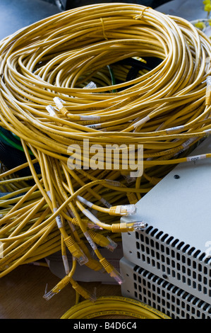 Jumble of yellow ethernet cables beside two network devices. Stock Photo