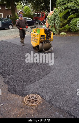 Home improvements gang of workers laying new tarmac domestic drive hot rolling flat Stock Photo