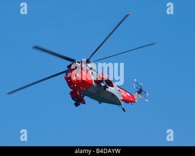 Royal Navy rescue helicopter flying across a clear blue sky Stock Photo