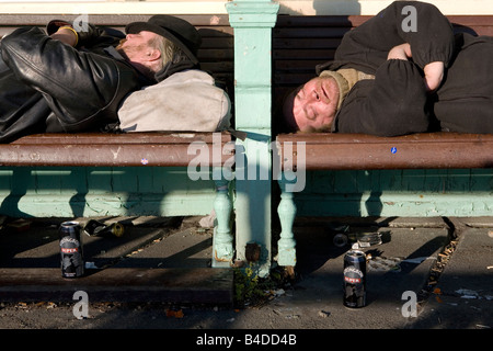 Two homeless men sleeping on a bench Stock Photo
