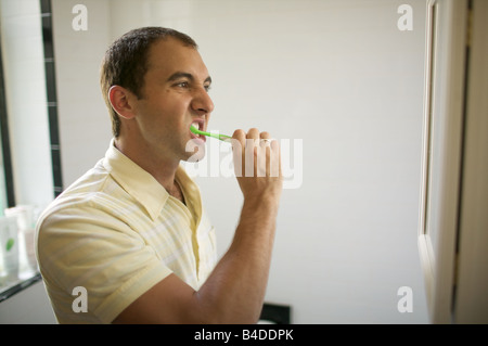 Profile of somewhat hairy yet pleasant man brushing his teeth. Early to bed, early to rise, makes a man healthy wealthy and wise Stock Photo