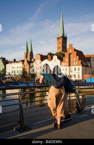 Two young people on river bridge looking at scenery Lubeck Germany Stock Photo