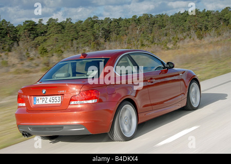 BMW 135i Coupe, driving, diagonal from the back, rear view, country road, red, model year 2007- Stock Photo