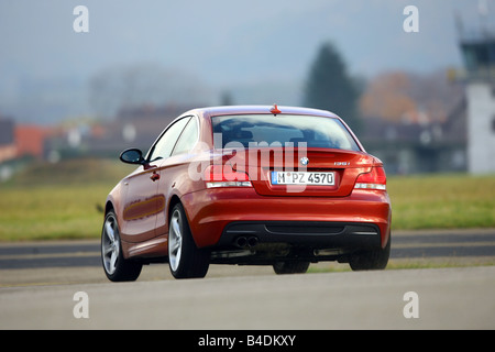 BMW 135i Coupe, driving, diagonal from the back, rear view, country road, red, model year 2007- Stock Photo