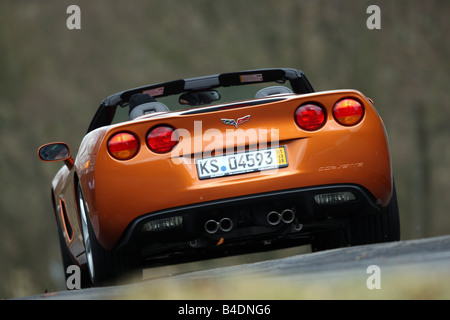Corvette C6, rust-red model year 2008, orange -metallic, driving, diagonal from the back, rear view, country road, open top Stock Photo