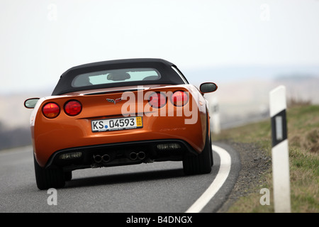 Corvette C6, rust-red model year 2008, orange -metallic, driving, diagonal from the back, rear view, country road, closed top Stock Photo