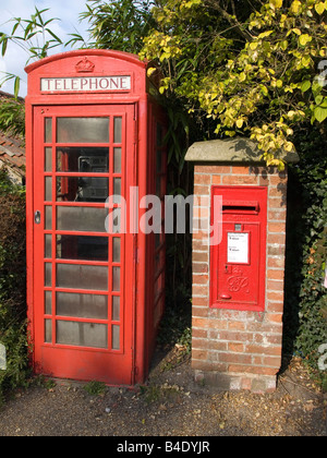 A bright red telephone box and a post box in a brick pillar in St James Street Dunwich Suffolk UK Stock Photo