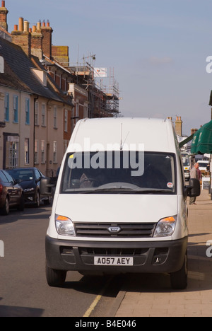 White van parked up on kerb in high street Stock Photo