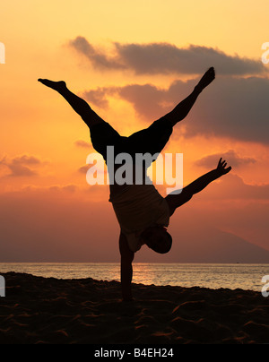 Young man is doing an amazing handstand at sunset Stock Photo