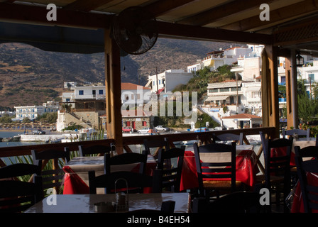 Empty Tables and Chairs in Taverna Overlooking Batsi Town and Harbour Isle of Andros Cyclades Islands Greece Stock Photo