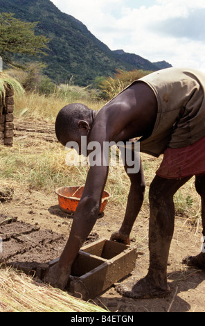 Brick maker using moulds, working on hill. Uganda. Stock Photo