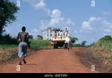 Man running after lorry carrying villagers, Uganda Stock Photo
