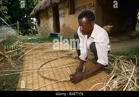 Male basket weaver preparing circular framework for basket, Uganda, Africa Stock Photo