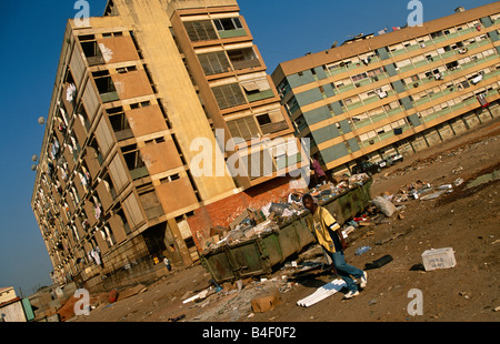 Man walking by garbage dump, residential buildings in background, Angola Stock Photo