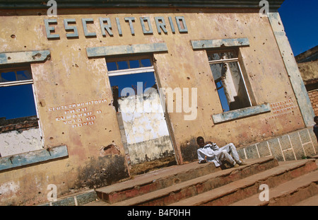 A homeless boy sitting on the steps of a destroyed building in Angola. Stock Photo