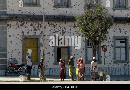 Women standing in front of bullet-riddled building in Angola Stock Photo