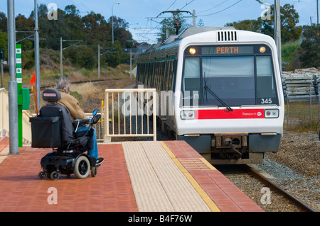 Person in a wheelchair waiting on the platform for a suburban train in Perth Western Australia Stock Photo