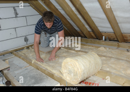 Fitting loft insulation in a house in Thornbury Gloucestershire England Stock Photo