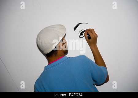A graffiti artist draws in a legal public show of their work. Stock Photo