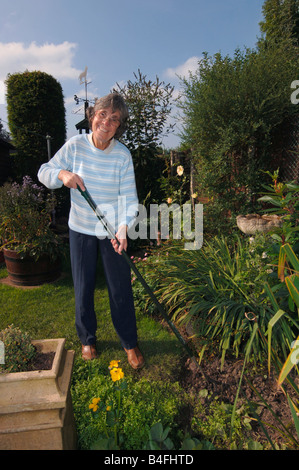 A Woman In Her Seventies Hoeing Her Garden Stock Photo