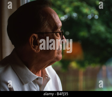 Elderly man looking out a window Stock Photo