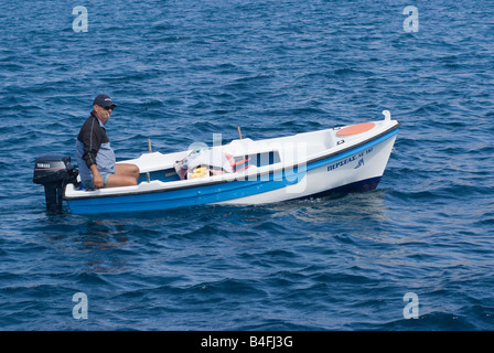 A Greek Fisherman in his Boat Smoking a Cigarette in Aegean Sea near Livadi Town Isle of Serifos Greece Stock Photo
