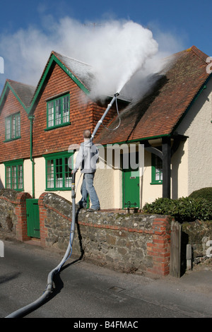 Blowing fake snow onto a cottage roof in the village of Shere, Surrey, for the film 'The Holiday' 2006 Stock Photo