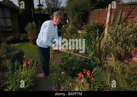 A Woman In Her Seventies Cleaning Out A Garden Pond Stock Photo