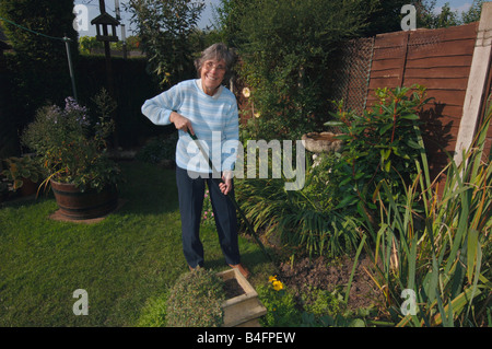 A Woman In Her Seventies Hoeing Her Garden Stock Photo