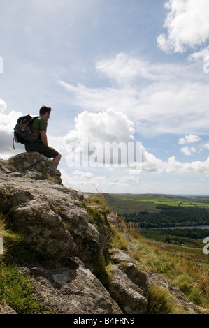 A Hiker on top of Leather Tor on Dartmoor looking out over Burrator Reservoir Stock Photo