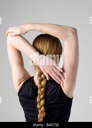 A young woman stretching here arm muscles, rear view Stock Photo