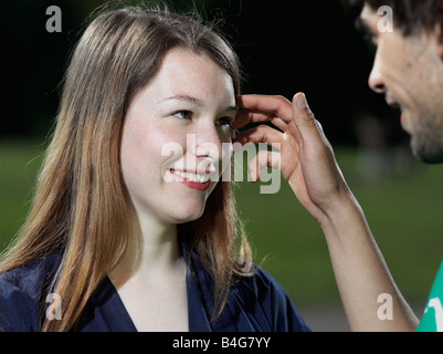 A young man pushing the hair back from a young woman's face Stock Photo