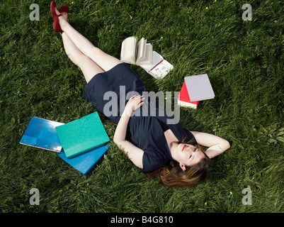 A young female student lying in the grass Stock Photo