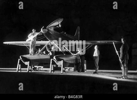 R J Mitchell Aircraft Designer August 1929 Working by searchlight on the Supermarine S6 engine at 10pm at night Reginald Mitchell the designer in his plus fours trousers seen at the right oversees work being carried out on the seaplane An armed guard stands nearby with his rifle and bayonet Stock Photo