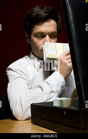 A man smelling a stack of money Stock Photo