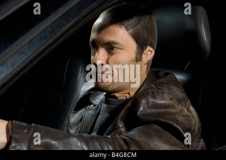 A man with a nylon over his face sitting in a car Stock Photo