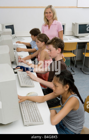 A teacher and four pre-adolescent children in a computer lab Stock Photo