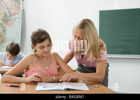 A teacher helping a student in a classroom Stock Photo