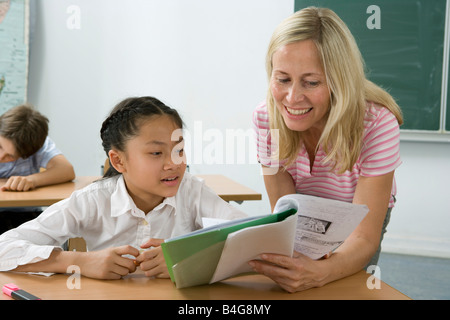 A teacher helping a student in a classroom Stock Photo