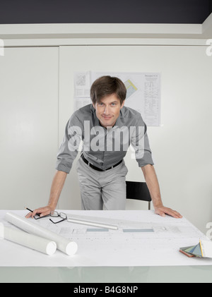 An architect leaning over blueprints on a desk Stock Photo